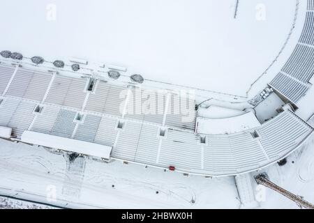Leeres Fußballstadion in der Wintersaison. stadionsitze und Fußballplatz mit Schnee bedeckt. Luftaufnahme von oben. Stockfoto