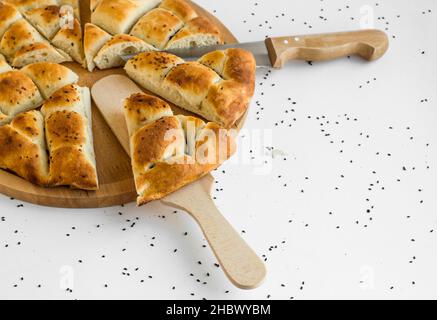 Triangle geschnittenes türkisches Ramadan-Brot, Pide auf dem Holzteller mit Spachtel und Messer. Stockfoto