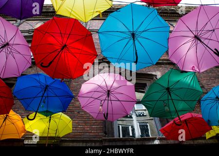 Bunte Regenschirme hängen vor dem historischen Gebäude an der Straße. Stockfoto