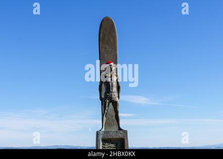 Surfer-Statue, Surfdenkmal, Bronze eines männlichen Surfers, der vor seinem mit Weihnachtsmütze und Weihnachtsleis geschmückten Brett steht für Christma Stockfoto