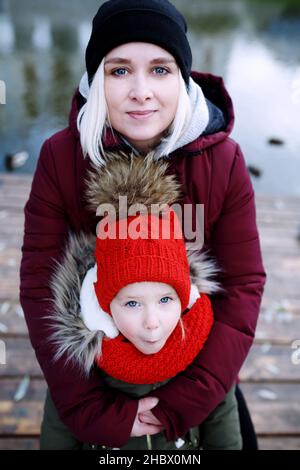 Junge Mutter, die mit ihrer niedlichen kleinen Tochter draußen im Stadtpark läuft Stockfoto