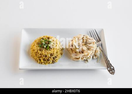 Bulgur-Pilaf mit Huhn und grünen Linsen in einem langen Teller mit Gabel gekocht Stockfoto