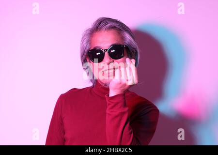 Der coole ältere asiatische Mann in der Gel-Farbe Lichtfotografie. Stockfoto