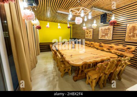 Handgefertigter großer Holztisch und Stühle auf dem Marmorboden. Stockfoto