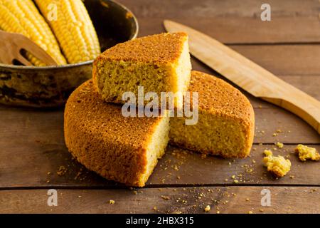 Frisch, in Scheiben geschnittenes Cornbread auf dem Holztisch mit Hühneraugen und Holzmesser. Stockfoto