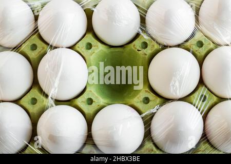 Frische, organische weiße Farbe, fünfzehn Eier auf Karton, in Stretchfolie gewickelt und ein Platz ist leer. Stockfoto