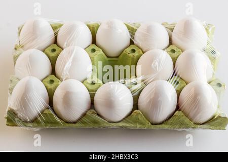 Frische, organische weiße Farbe, fünfzehn Eier auf Karton, in Stretchfolie gewickelt und ein Platz ist leer. Stockfoto