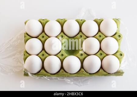 Frische, organische weiße Farbe, fünfzehn Eier auf Karton, in Stretchfolie gewickelt und ein Platz ist leer. Stockfoto