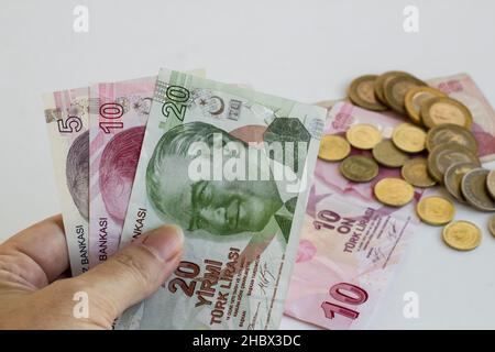 Hand hält türkische Banknoten; zwanzig, zehn und fünf Lira aganist andere Lira auf weißem Hintergrund. Stockfoto