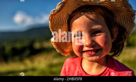 Ein junges Mädchen, das in den Bergen lächelt. Stockfoto