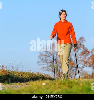 Junge Frau beim entspannten Nordic Walking in herbstlicher Natur Stockfoto