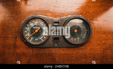 Alter Kilometerzähler und Tachometer in Kilometern pro Stunde auf altem hölzernen Armaturenbrett Stockfoto