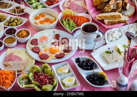 Traditionelles türkisches Frühstück mit Wachteleiern und Würstchen auf der Mitte des Tisches mit einer Tasse Tee. Stockfoto
