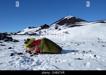 Winterbasislager am Vulkankrater im Ätna Park, Wanderer mit Rucksack schließt das Zelt [1a] Stockfoto