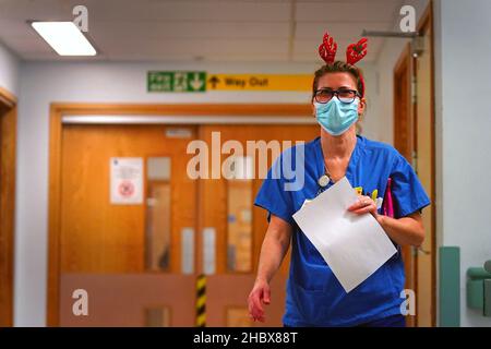 Ein Mitarbeiter des medizinischen Personals, das ein Paar festlicher Geweihe auf der Arbeitsstation im King's College Hospital im Südosten Londons trägt. Bilddatum: Dienstag, 21. Dezember 2021. Stockfoto