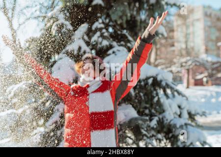 Positive Teenager-Mädchen liebt Winter, frostigen schneebedeckten sonnigen Tag, Schnee. Spielen mit Schnee, wirft Kind weißen losen Schnee in die Luft. Waldspaziergang Stockfoto