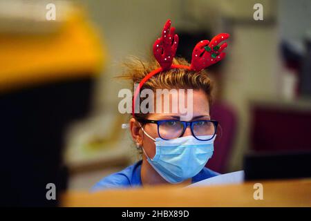 Ein Mitarbeiter des medizinischen Personals, das ein Paar festlicher Geweihe auf der Arbeitsstation im King's College Hospital im Südosten Londons trägt. Bilddatum: Dienstag, 21. Dezember 2021. Stockfoto