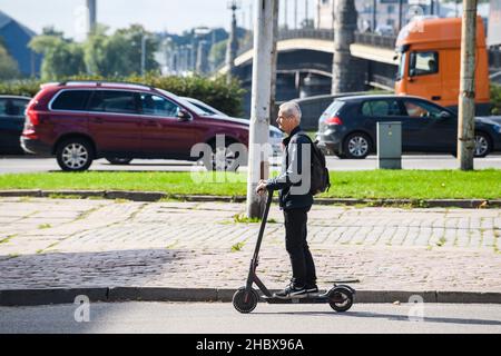 RIGA, LETTLAND. 8th. September 2021. Ein Mann fährt mit einem Elektroroller. Stockfoto