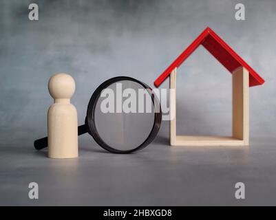 Haussuche, Immobilienbewertung, Immobilienbewertung Konzept. Vergrößerungsglas, Holzpuppen und Haus. Stockfoto