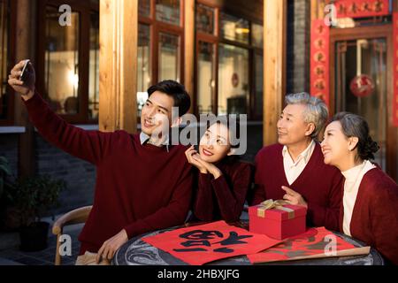 Glückliche Familie, die am Neujahrstag mit ihrem Smartphone Selfies macht Stockfoto