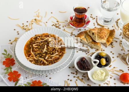 Traditionelles türkisches Ramadan-Iftar-Gericht mit grüner Linsensuppe, Brotscheiben und Tee auf Weiß. Stockfoto