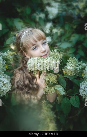 Schöne 11-jährige Mädchen mit langen blonden Haaren in Hortensien Blumen. Bild von einem charmanten kleinen Prinzessin. Stockfoto