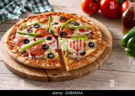 Traditionelle, erstklassige Pizza auf einem rustikalen Holztisch Stockfoto