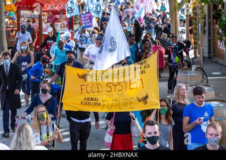 Demonstranten, die durch London mit einer großen Flagge mit einem pflanzlichen Ernährungssystem gehen Stockfoto