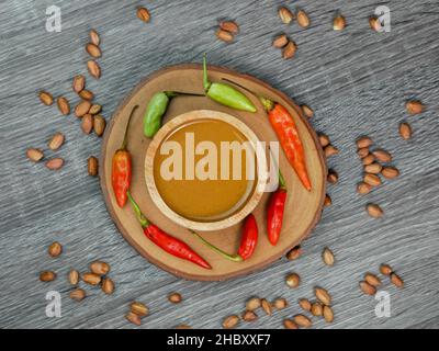Erdnusssauce in einer kleinen Holzschüssel auf einem grauen Holztextur-Hintergrund. Stockfoto