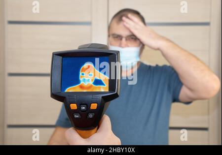 Die Körpertemperatur der Person wird mit einer Wärmebildkamera gemessen. Selektiver Fokus. Temperaturanstieg wird auf dem Bildschirm angezeigt Stockfoto