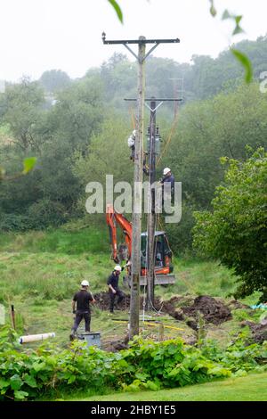 Stromarbeiter ersetzen den alten Strommast und verbinden Stromkabel auf einem ländlichen Grundstück in Wales Großbritannien KATHY DEWITT Stockfoto