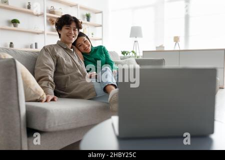 Millennial Asian paar Filme auf Laptop-Computer online, Kuscheln auf der Couch zu Hause, kopieren Raum Stockfoto