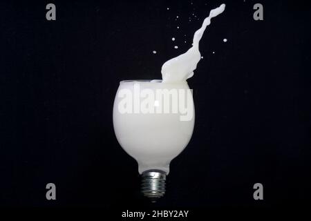 Milchspritzer in einer Glühbirne, isoliert auf Schwarz Stockfoto