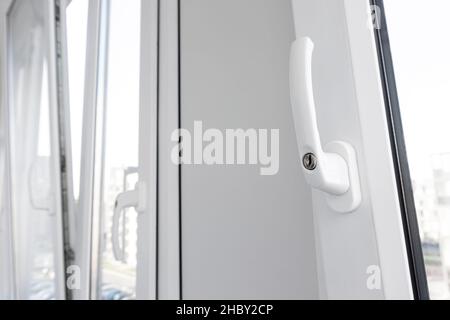 Geöffneter weißer Kunststofffenstergriff in aufrechter Nahaufnahme. Neue kippbare und drehbare pvc-Fensterlüftung. Stockfoto