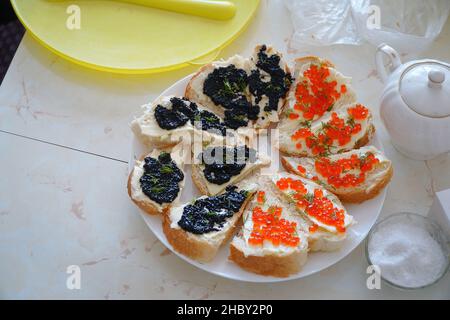 Sandwiches mit rotem und schwarzem Kaviar auf einem Teller auf dem Tisch Stockfoto