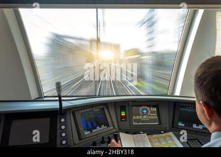 Der Zugführer steuert die Kabine des Geschwindigkeits-Personenzuges, Blick auf die Eisenbahnbrücke mit dem Effekt der Geschwindigkeitsbewegung Stockfoto