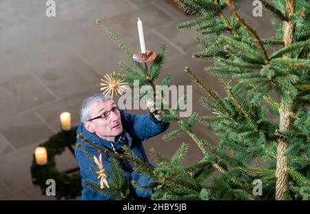 22. Dezember 2021, Sachsen, Meißen: Dompfarrer Stephan Kühne schmückt den Weihnachtsbaum im Altarbereich des Meissener Doms auf der Albrechtsburg. Der Bau der gotischen Kirche begann Ende des 13th. Jahrhunderts. Foto: Matthias Rietschel/dpa-Zentralbild/ZB Stockfoto