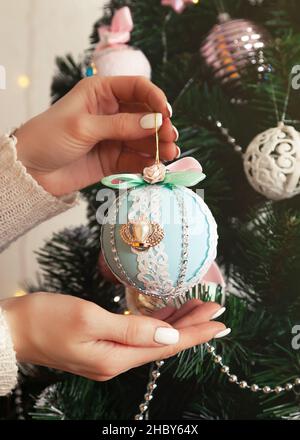 Nahaufnahme der weiblichen Hände hängen den Ball auf den Baum. Weihnachten de Stockfoto