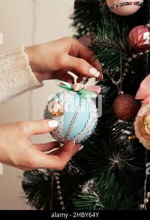 Nahaufnahme der weiblichen Hände hängen den Ball auf den Baum. Weihnachten de Stockfoto
