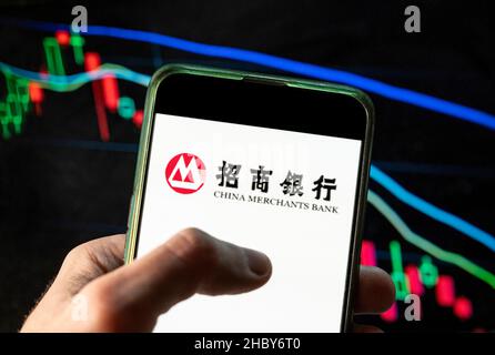 China. 09th Dez 2021. In dieser Abbildung ist das Logo des chinesischen staatlichen Banken- und Finanzkonzerns China Merchants Bank zu sehen, das auf einem Smartphone mit einem Index-Diagramm der wirtschaftlichen Börse im Hintergrund zu sehen ist. (Foto von Budrul Chukrut/SOPA Images/Sipa USA) Quelle: SIPA USA/Alamy Live News Stockfoto