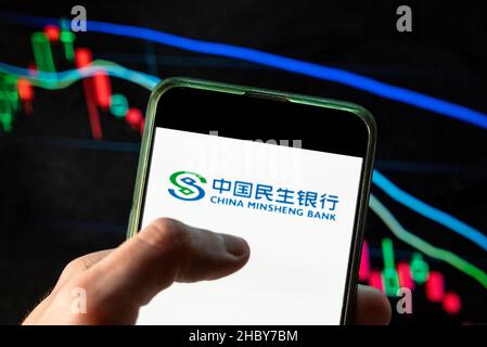 China. 4th Dez 2021. In dieser Abbildung sehen Sie das Logo der chinesischen Bank-, Treuhandgesellschaft- und Investmentgesellschaft China Minsheng Bank, das auf einem Smartphone mit einem wirtschaftlichen Börsenindex-Diagramm im Hintergrund zu sehen ist. (Bild: © Budrul Chukrut/SOPA Images via ZUMA Press Wire) Stockfoto