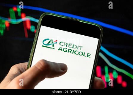 China. 4th Dez 2021. Auf dieser Fotolabbildung ist das Logo des größten französischen kooperativen Finanzinstituts Credit Agricole zu sehen, das auf einem Smartphone mit einem Index-Diagramm der wirtschaftlichen Börse im Hintergrund zu sehen ist. (Bild: © Budrul Chukrut/SOPA Images via ZUMA Press Wire) Stockfoto