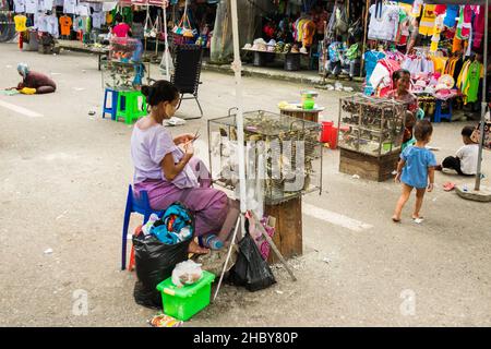 YANGON, MYANMAR (BURMA) - 19. Aug 2017: Eine burmesische Frau mit Thanakha im Gesicht verkauft Vögel außerhalb der Shwedagon-Pagode. Vögel, die von Überkr. Freigesetzt wurden Stockfoto