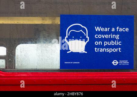 Tragen Sie am nassen Tag im August eine Gesichtsbedeckung auf dem Schild mit öffentlichen Verkehrsmitteln im alten Londoner Bus bei der Veranstaltung „Tag der offenen Tür“ von Imberbus in Salisbury Plain, Wiltshire, Großbritannien Stockfoto