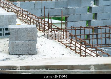 Nahaufnahme von Blöcken und Armaturen auf einer Baustelle. Bauphasen. Das Haus besteht aus Schlackenblöcken mit hervorstehenden Armaturen, Erdgeschoss. Stockfoto