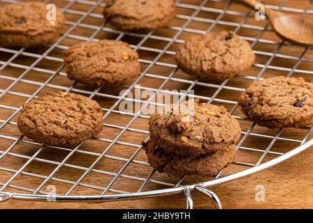 Blick auf frisch gebackene leckere hausgemachte Schokoladensplitter-Butterkekse auf dem Kühlregal auf dem Holztisch. Stockfoto