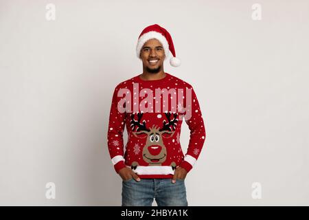 Glücklicher schwarzer Kerl in Weihnachtsmütze und Pullover mit Hirsch Stockfoto