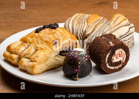 Variation aus köstlichem Dessert, dänischem Gebäck mit Schokoladencreme-Füllung, Schokoladenbrot, Schwarzwälder Schokoladenrolle und Choc Balls toppi Stockfoto