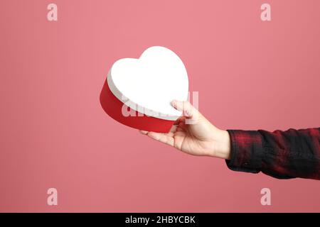 Der asiatische Mann Hand hält Geschenk für jemanden auf dem rosa Hintergrund zu geben. Stockfoto