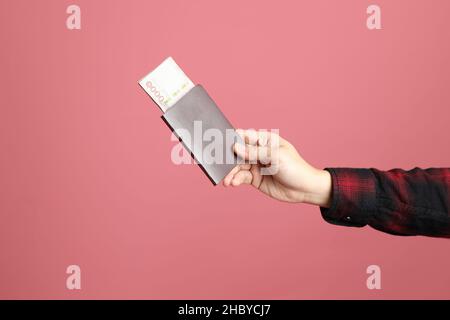 Der asiatische Mann Hand hält Geld für jemanden auf dem rosa Hintergrund zu geben. Stockfoto